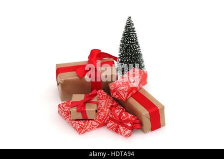 Weihnachtsgeschenke mit roten Bändern und Schleifen vor einem Weihnachtsbaum vor einem weißen Hintergrund Stockfoto