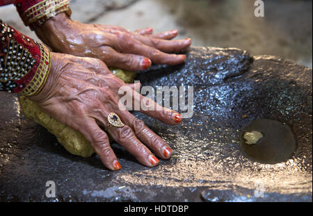 Traditionell gekleidete alte omanischen Frau drücken Nussöl mit ihren Händen. Stockfoto