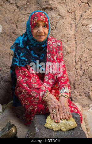 Traditionell gekleidete alte omanischen Frau drücken Nussöl mit ihren Händen. Stockfoto