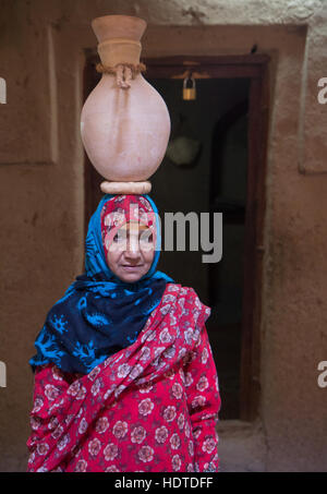 Traditionell gekleidete alte omanischen Frau einen Tontopf auf dem Kopf tragen. Stockfoto