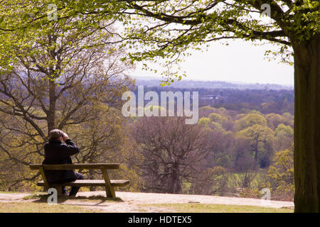 ein einsamer Mann auf einer Bank sitzend blickt die herrliche Aussicht auf London an einem sonnigen Wintermorgen in Richmond Park, London auf Stockfoto