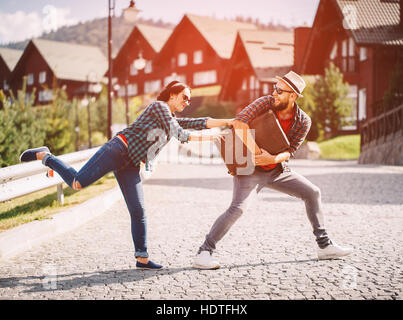 Liebespaar kämpfen für den Koffer auf der Straße. Stockfoto