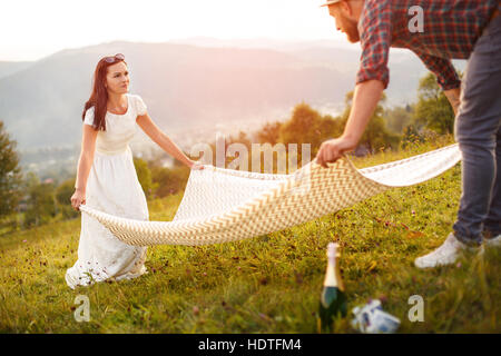 paar in Liebe Picknick vorbereiten. weißen Plaid zu verbreiten. Stockfoto