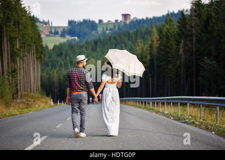 Liebespaar zu Fuß entlang der Straße im Wald Stockfoto