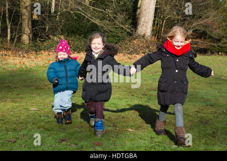 Drei Schwestern: Mädchen Alter 4, 2 & 6 Jahre, vier, zwei und sechs Jahre alt, laufen laufen spielen im Rasen Park / Park / UK Herbst. Stockfoto