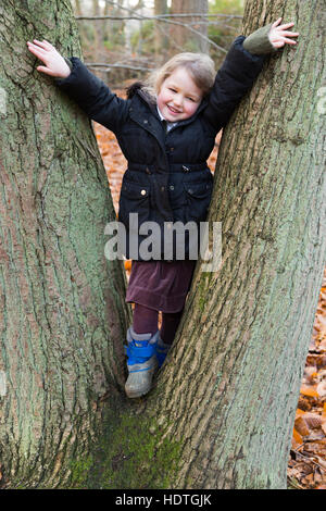 Mädchen Alter 4 Jahre/vier Jahre alten Umarmungen festhalten an Bäumen / Klettern Klettern / klettert Baum umarmen / spielt / spielen in Holz / Herbst. UK Stockfoto