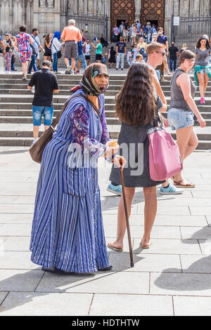 Muslimische ältere Frau Bettler gekleidet in eine Burka Betteln auf einem Platz in Barcelona, Spanien Stockfoto