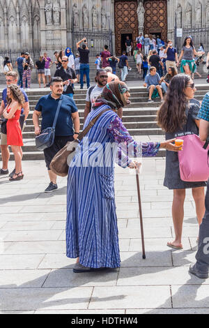 Muslimische ältere Frau Bettler gekleidet in eine Burka Betteln auf einem Platz in Barcelona, Spanien Stockfoto