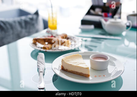 Stück Käsekuchen auf weißen Teller und Glas Tisch im café Stockfoto