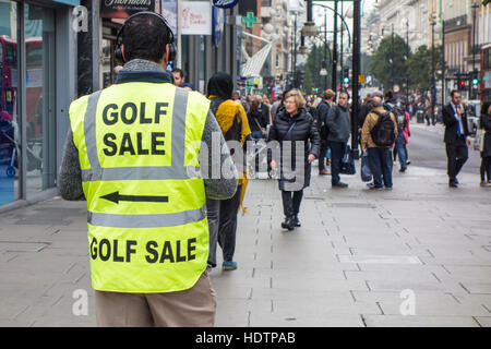 Käufer übergeben Mann trägt Warnschutz-Jacke mit Golf Verkauf Werbeschild. Oxford Street, London Stockfoto