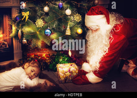 Der Weihnachtsmann brachte ein Geschenk für das schlafende Mädchen. Stockfoto