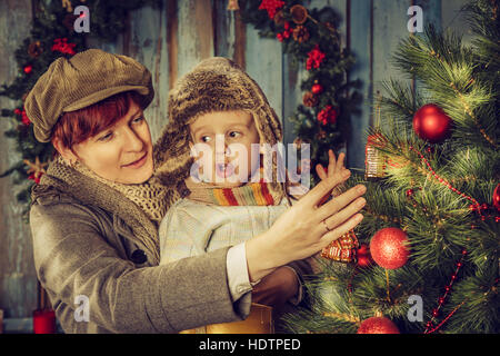 Mutter und Sohn einen Weihnachtsbaum zu verzieren. Weihnachtskarte. Stockfoto