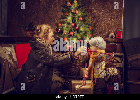 Mutter und Sohn einen Weihnachtsbaum zu verzieren. Weihnachtskarte. Stockfoto