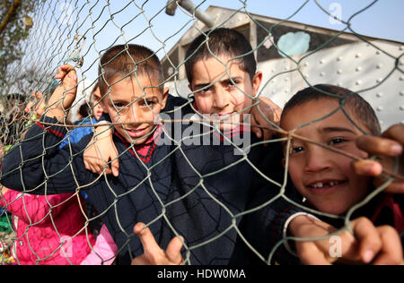 Syrische Flüchtlingskinder peep durch die Umzäunung von einem alten ehemaligen Basketballplatz, die jetzt ihren Schulhof in einem Flüchtlingslager in der Nähe von Taalabaya im Bekaa-Tal. Stockfoto