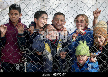 Syrische Flüchtlingskinder peep durch die Umzäunung von einem alten ehemaligen Basketballplatz, die jetzt ihren Schulhof in einem Flüchtlingslager in der Nähe von Taalabaya im Bekaa-Tal. Stockfoto