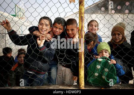 Syrische Flüchtlingskinder peep durch die Umzäunung von einem alten ehemaligen Basketballplatz, die jetzt ihren Schulhof in einem Flüchtlingslager in der Nähe von Taalabaya im Bekaa-Tal. Stockfoto