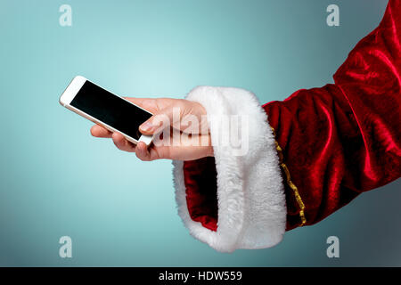 Santa Claus halten Handys bereit für Weihnachten auf blauen Studio-Hintergrund Stockfoto