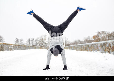 Junger Mann macht Handstand im Winter Stockfoto