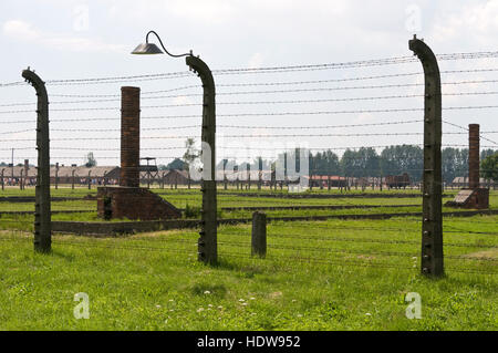 Die Überreste von Schornsteinen, die Teil der Gefängnisgebäude hinter hohen Widerhaken Drahtzäune in 11 Auschwitz-Birkenau in Oswiecim, Polen Stockfoto