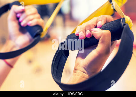 TRX. Weibliche Hände mit Fitness TRX Riemen im Fitness-Studio. Stockfoto