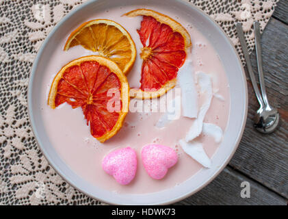 Rosa-Smoothies mit Himbeere, Kokos, Orangen und Müsli.  Frühstück am Valentinstag. Stockfoto