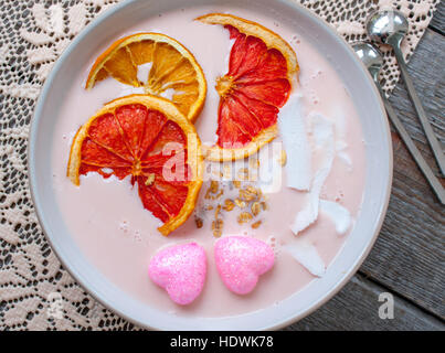 Rosa-Smoothies mit Himbeere, Kokos, Orangen und Müsli.  Frühstück am Valentinstag. Stockfoto