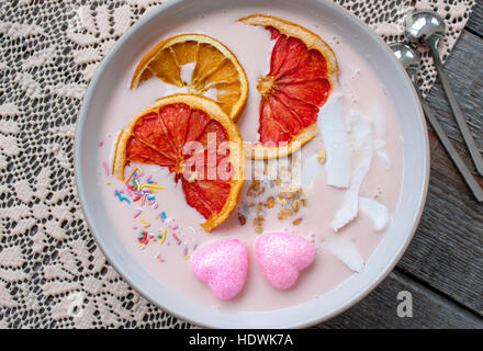 Rosa-Smoothies mit Himbeere, Kokos, Orangen und Müsli.  Frühstück am Valentinstag. Stockfoto