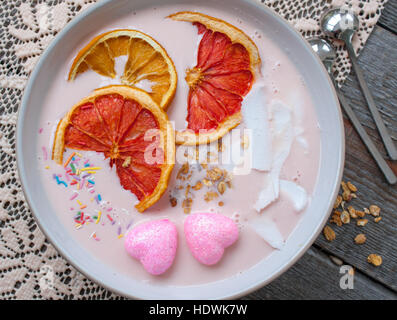 Rosa-Smoothies mit Himbeere, Kokos, Orangen und Müsli.  Frühstück am Valentinstag. Stockfoto