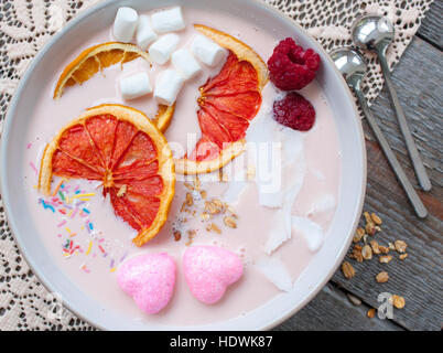 Rosa-Smoothies mit Himbeere, Kokos, Orangen und Müsli.  Frühstück am Valentinstag. Stockfoto