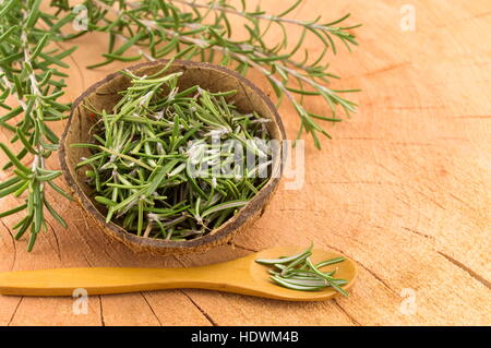 Rosmarin in einer Kokosnussschale mit einem Holzlöffel Stockfoto