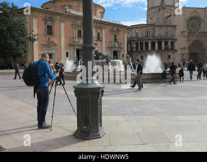 Fotograf, der Stativ und Kamera aufstellt, um Touristen am Turia-Brunnen auf der Plaza de la Virgen, Valencia, Spanien, zu fotografieren Stockfoto