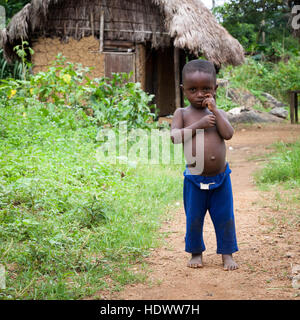 Kleiner Junge posiert vor Thatchered Hütte Stockfoto