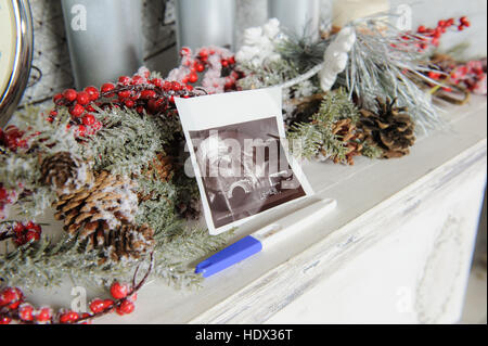 Ultraschallbild und ein Schwangerschaftstest mit Weihnachts-Dekor. Close-up. Stockfoto