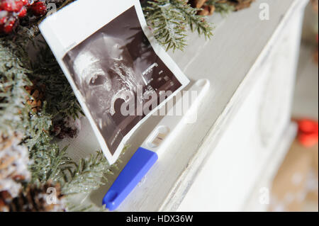 Ultraschallbild und ein Schwangerschaftstest mit Weihnachts-Dekor. Close-up. Stockfoto