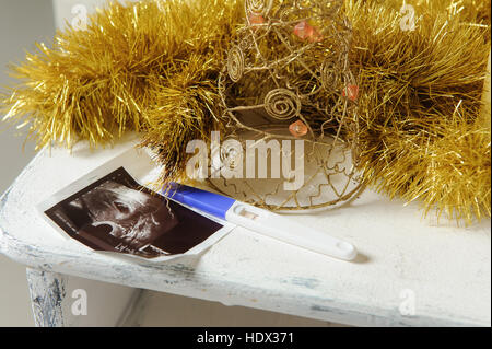 Ultraschallbild und ein Schwangerschaftstest mit Weihnachts-Dekor. Close-up. Stockfoto