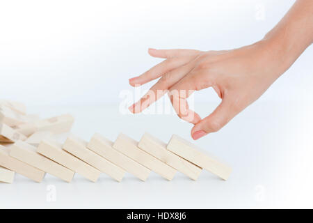 Menschliche Hand beginnend ein Domino-Effekt-Konzept mit Holzklötzen Stockfoto