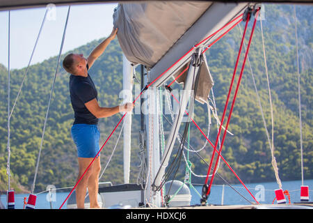 Segler zieht das Seil, das Segel Segelboot zu kontrollieren. Stockfoto