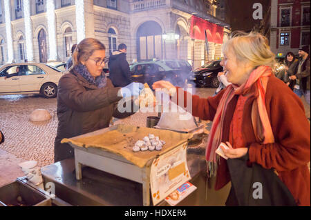 Eine Frau kauft heißen Maroni aus einem Straßenhändler in Praça Dom Pedro lV, Lissabon Portugal Stockfoto