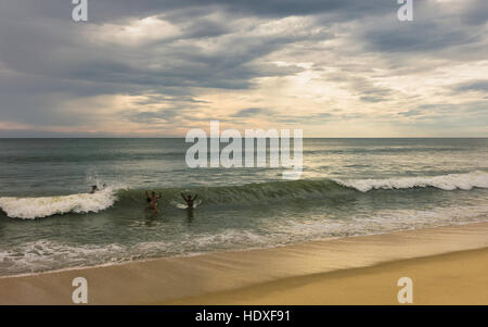 Die Einheimischen genießen Sie ein Bad in der Dämmerung an einem einsamen Strand in der Nähe in Thottada mit dem arabischen Meer und Himmel als Hintergrund zu beruhigen. Stockfoto