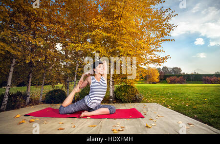 Junge Frau beim Yoga im Herbst Stadtpark in der Nähe von Birken gelb Stockfoto