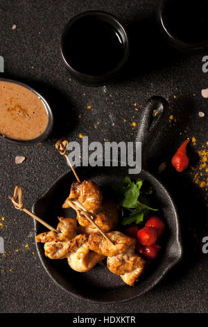 Chicken Satay auf einem dunklen Hintergrund mit Sauce Stockfoto