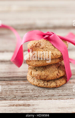 Glutenfreie Chocolate Chip Cookie Haufen mit Pink Ribbon auf rustikalen hölzernen Hintergrund Stockfoto