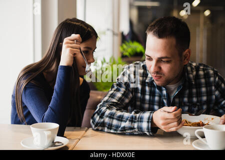 Lustige paar essen Nudeln im Café. Er will nicht seine Nahrung mit Freundin teilen Stockfoto