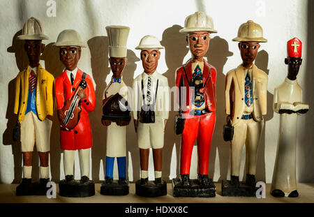 Afrikanische Souvenirs, Kolonialfiguren aus Holz zeigen verschiedene Berufe wie Koch Priester Fotograf Musiker Angestellte mit tropischem Helm oder Pith Helm Stockfoto