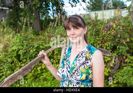Junge attraktive Frau mit Holzbalken im Sommer Stockfoto