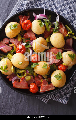 Kartoffeln mit gebratenem Speck und Kräuter auf einem Teller, Ansicht von oben senkrecht Stockfoto