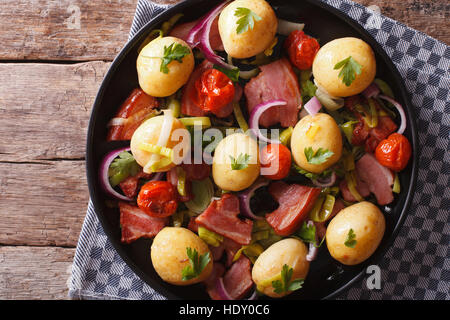 Rustikales Essen: Kartoffeln, Zwiebeln, Tomaten und Speck auf einem Teller. horizontale Ansicht von oben Stockfoto