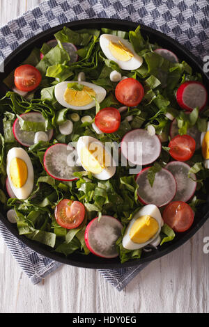 Frühlingssalat mit Eiern, Tomaten, Radieschen und Sauerampfer hautnah auf einem Teller. vertikale Ansicht von oben Stockfoto