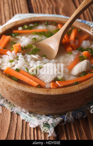 Hausgemachtes Essen: Hähnchen-Reis-Suppe hautnah in einer Holzschale. vertikale Stockfoto