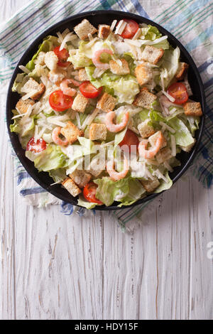 Caesar Salat mit Garnelen auf einer schwarzen Platte. vertikale Ansicht von oben Stockfoto